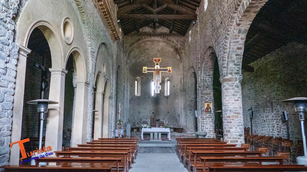 l'Interno della Pieve di Sorano, si vedono le  navate ad archi, l'altare e le panche in legno